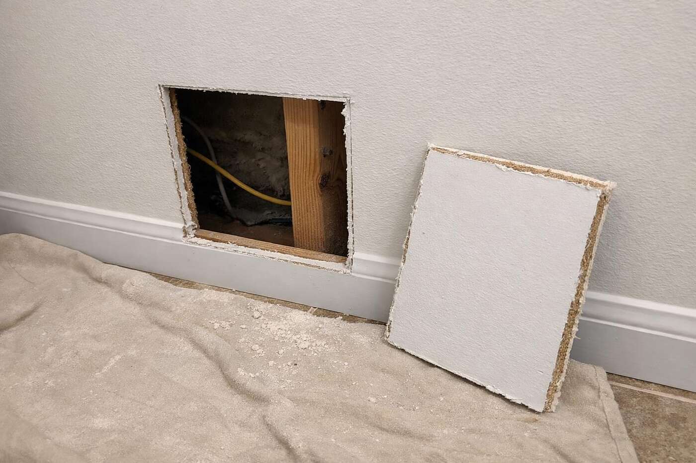 A small access opening cut into a drywall wall