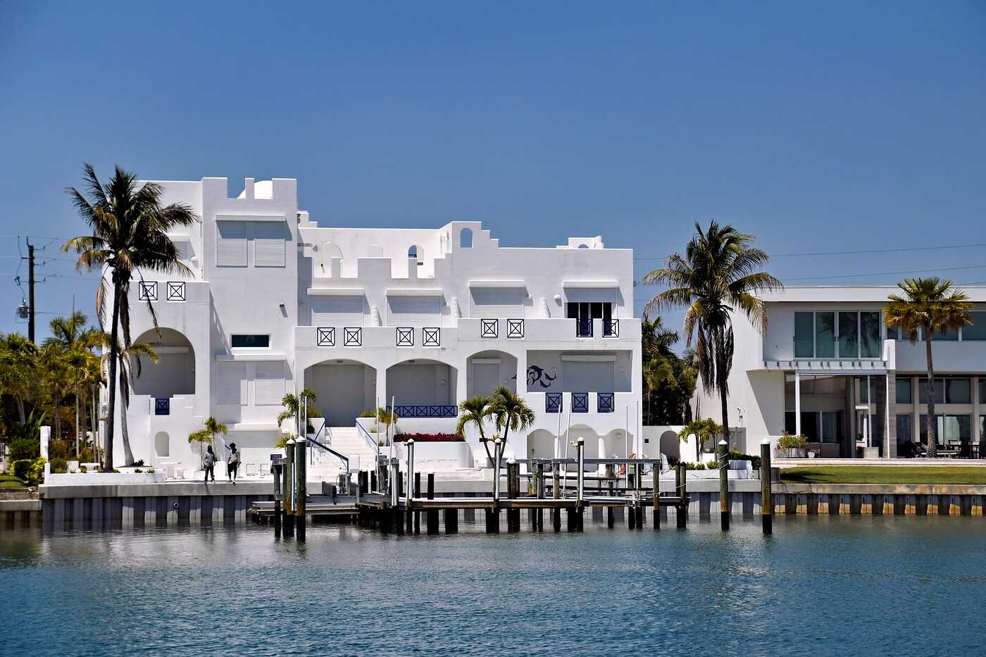 A white modern waterfront house beside a calm waterway