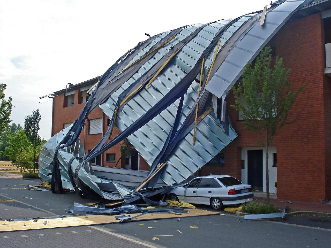 A flat roof covering peeled back by storm wind